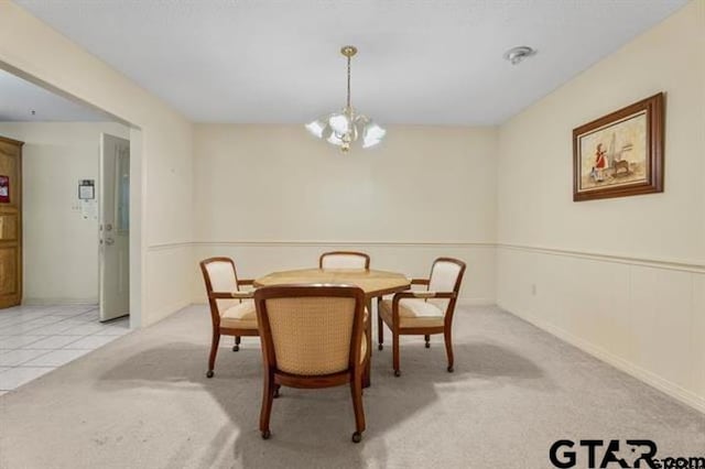 dining space featuring light carpet and a chandelier