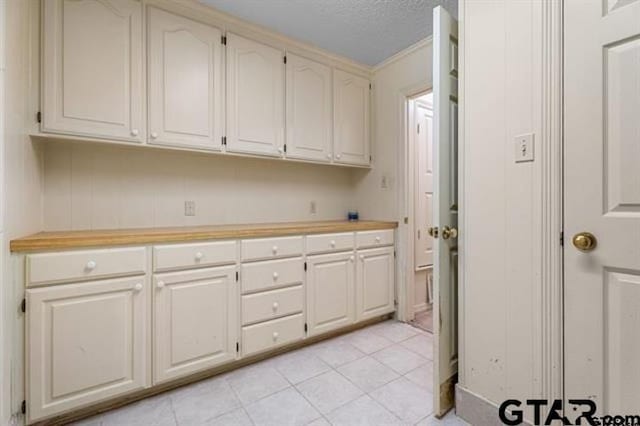 laundry room with light tile patterned flooring, crown molding, and a textured ceiling