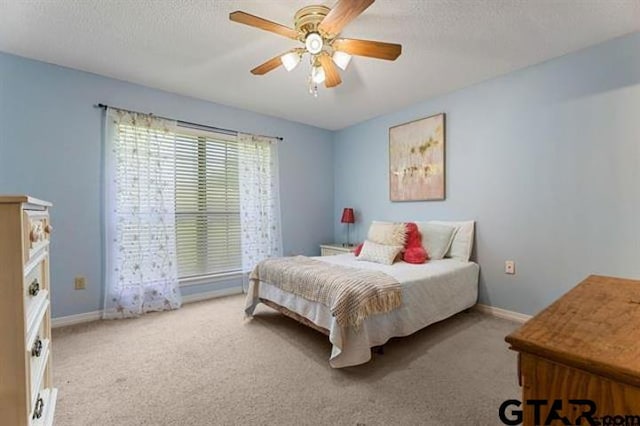 bedroom with ceiling fan, carpet floors, and a textured ceiling