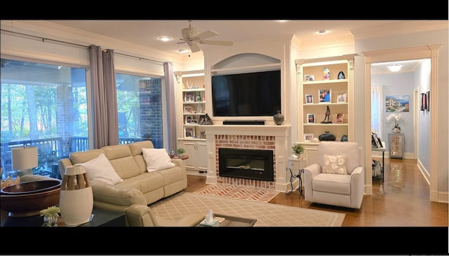 living room featuring built in features, ornamental molding, hardwood / wood-style floors, a brick fireplace, and ceiling fan