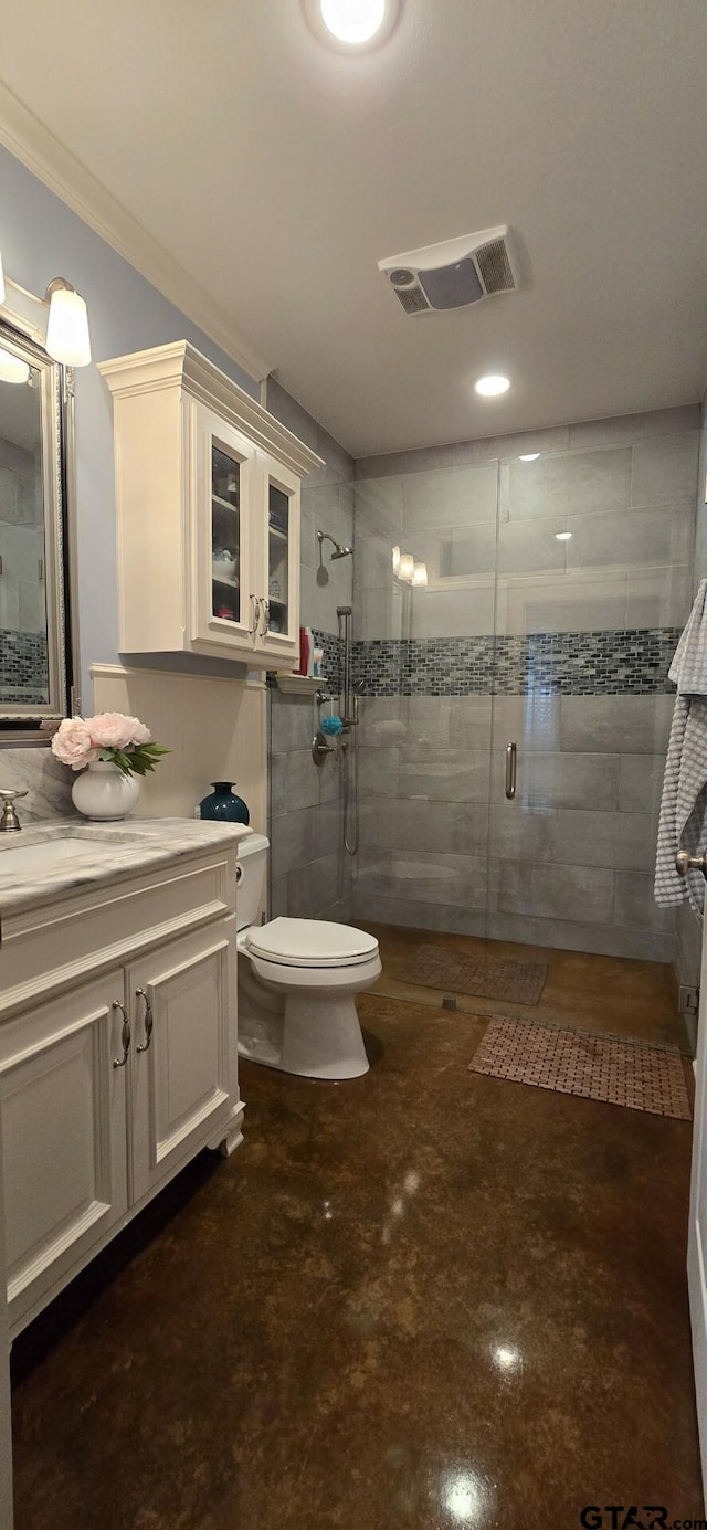 bathroom with toilet, vanity, ornamental molding, and a shower with shower door