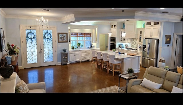 kitchen featuring stainless steel appliances, a breakfast bar, ornamental molding, a center island, and french doors