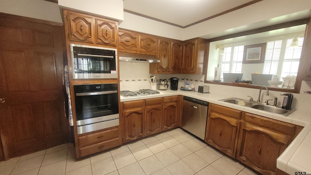 3802 Allendale Dr, Tyler, TX 75701 - kitchen featuring appliances with stainless steel finishes, a sink, under cabinet range hood, tile countertops, and brown cabinetry
