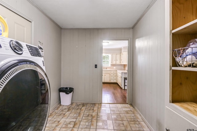 laundry area with wooden walls, sink, crown molding, and washer / dryer