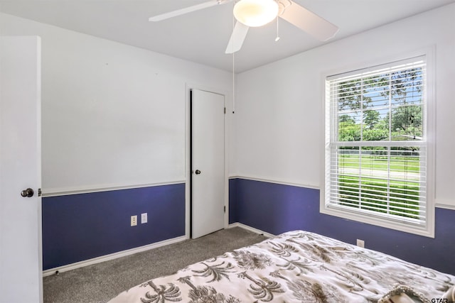 unfurnished bedroom with ceiling fan and dark carpet