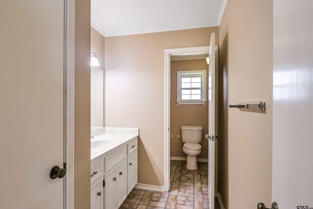 bathroom featuring toilet, vanity, and ornamental molding