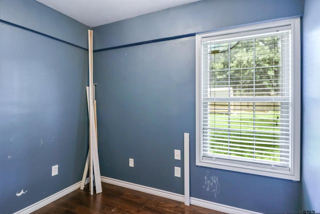 spare room with dark hardwood / wood-style floors and plenty of natural light