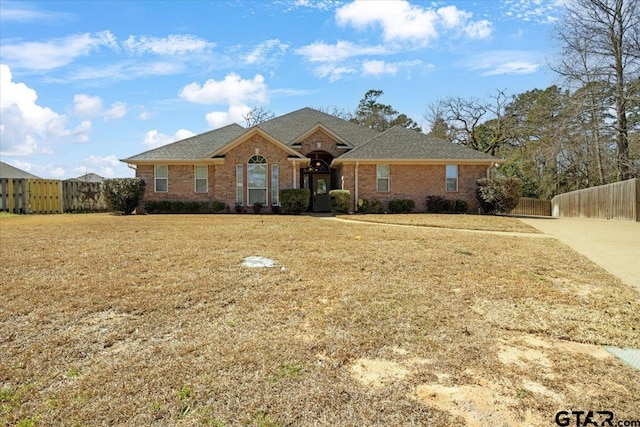 view of front of home featuring brick siding, fence, and a front yard