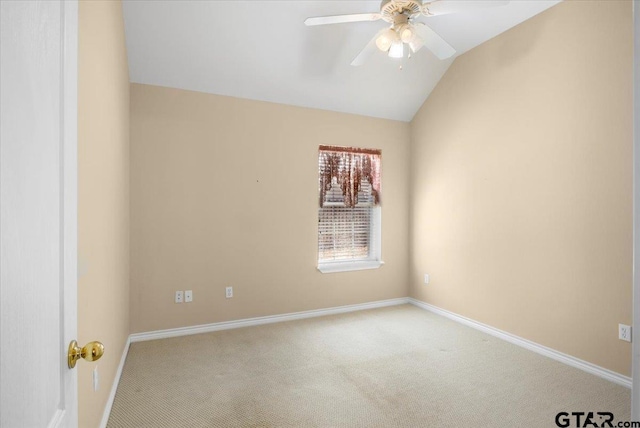 spare room featuring carpet flooring, vaulted ceiling, baseboards, and ceiling fan