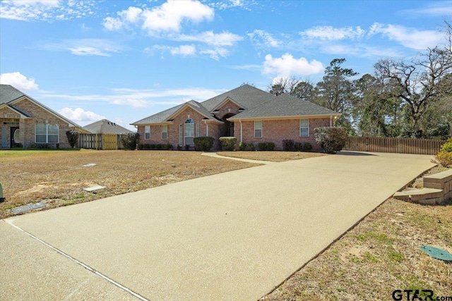 view of front of house with concrete driveway, brick siding, and fence