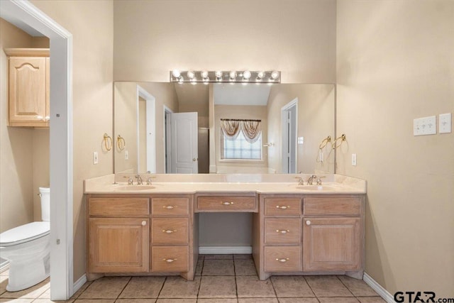 bathroom featuring double vanity, a sink, toilet, and tile patterned floors