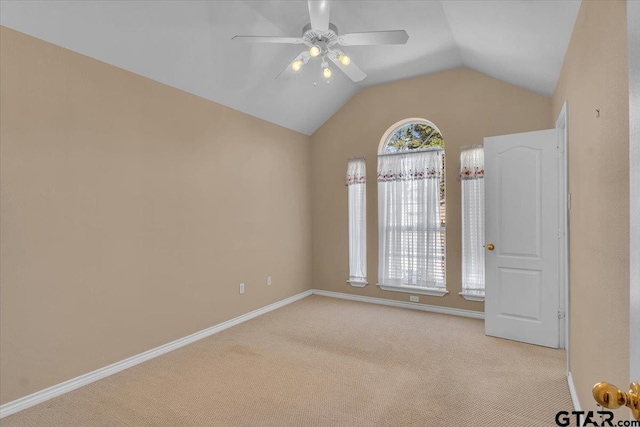 spare room featuring lofted ceiling, carpet, baseboards, and a ceiling fan