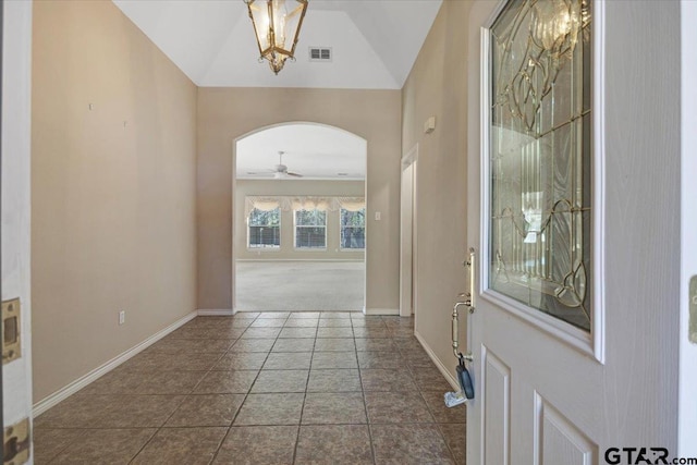 entrance foyer featuring baseboards, visible vents, arched walkways, vaulted ceiling, and ceiling fan with notable chandelier