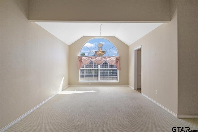 empty room featuring vaulted ceiling, carpet floors, an inviting chandelier, and baseboards