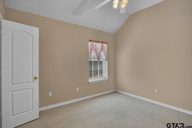 carpeted empty room featuring vaulted ceiling, baseboards, and ceiling fan