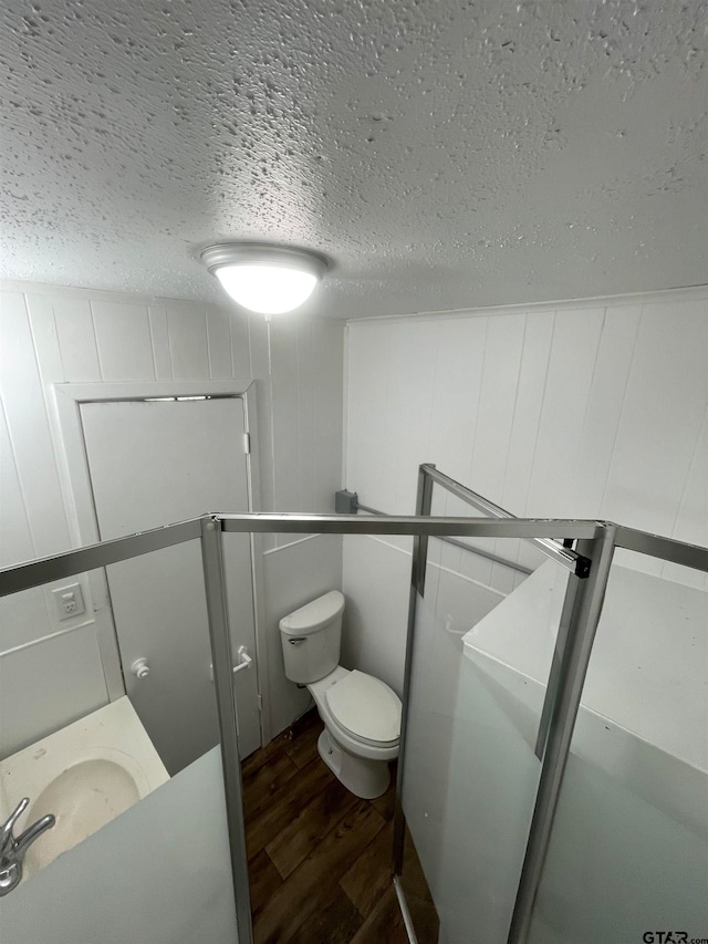 bathroom featuring toilet, wood-type flooring, and a textured ceiling