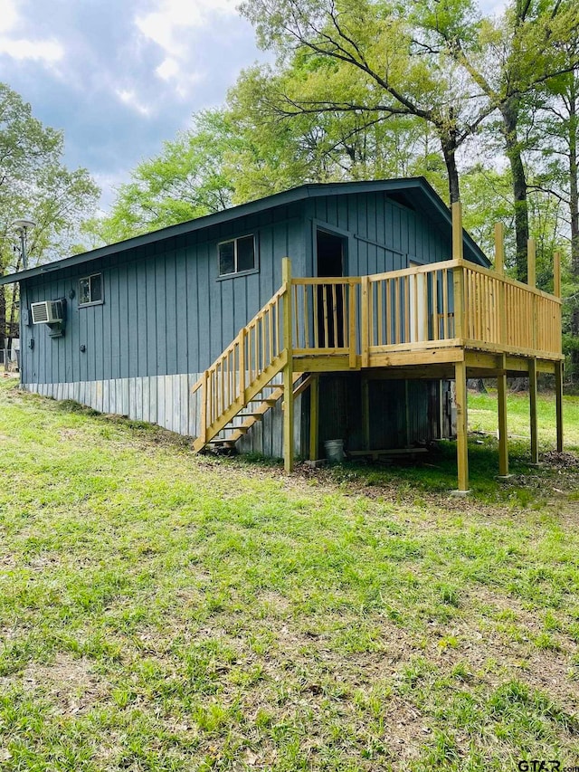 rear view of house with a lawn, a wooden deck, and a wall mounted air conditioner