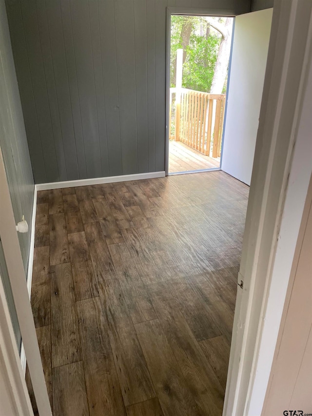 spare room featuring dark wood-type flooring and wood walls