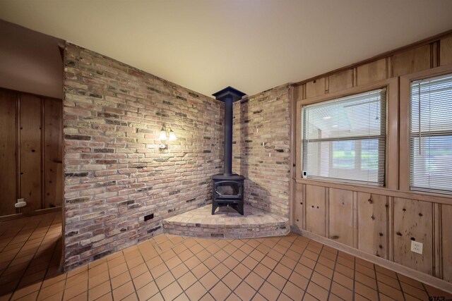 2929 Dinah Ln, Tyler, TX 75701 - unfurnished living room featuring tile patterned floors, wood walls, a wood stove, and brick wall
