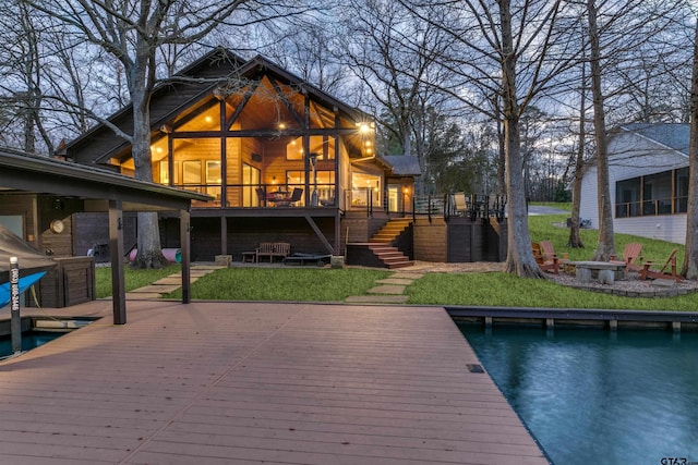 dock area featuring a wooden deck, a lawn, stairs, and an outdoor fire pit