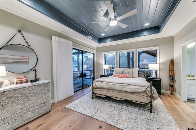 bedroom with light wood finished floors, ornamental molding, a tray ceiling, and access to outside