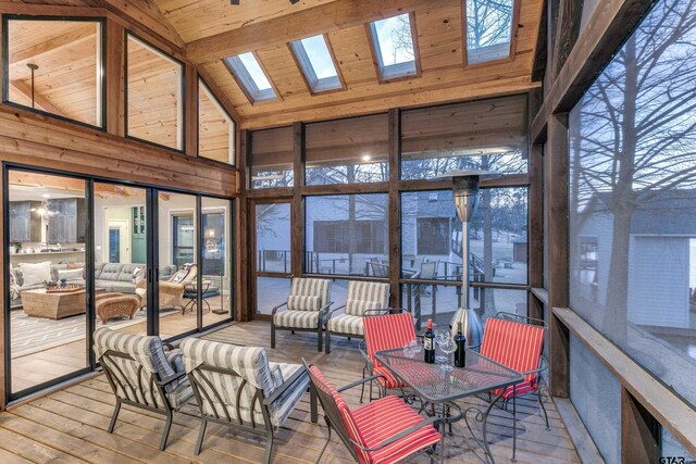 sunroom with lofted ceiling with skylight, plenty of natural light, and wooden ceiling