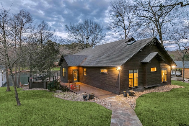 exterior space with a yard, roof with shingles, and a deck