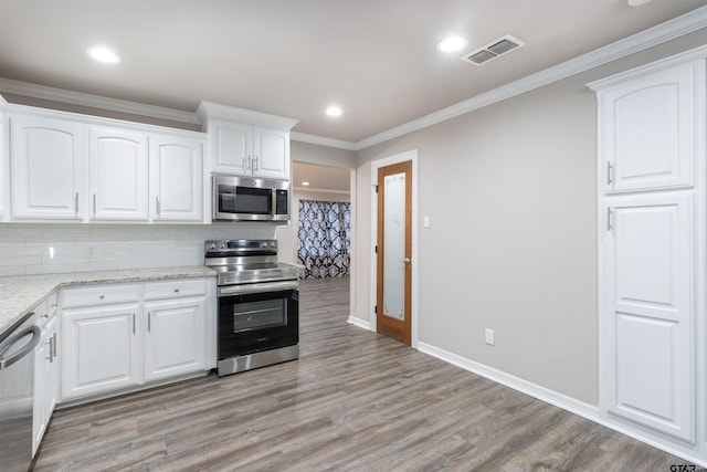 kitchen featuring visible vents, light wood-type flooring, ornamental molding, appliances with stainless steel finishes, and tasteful backsplash