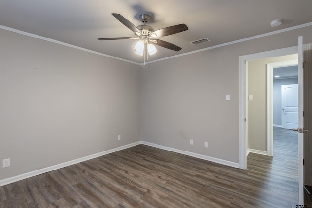 spare room with crown molding, dark wood-style floors, visible vents, and baseboards