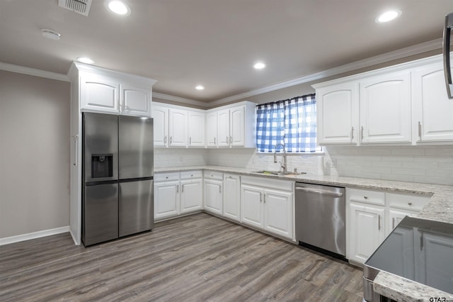 kitchen with visible vents, a sink, wood finished floors, stainless steel appliances, and crown molding