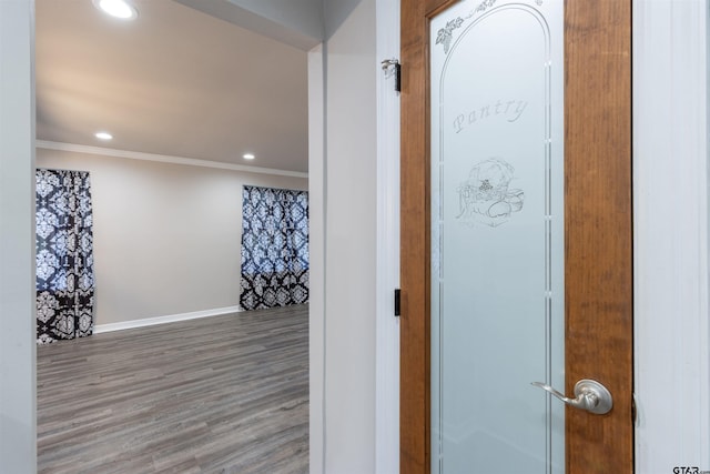 corridor featuring wood finished floors, recessed lighting, baseboards, and ornamental molding