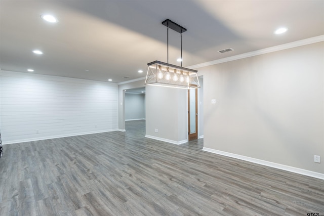 empty room featuring wood finished floors, visible vents, baseboards, recessed lighting, and ornamental molding