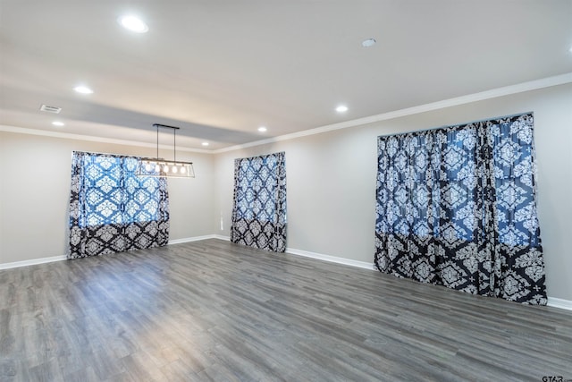 spare room with wood finished floors, baseboards, visible vents, recessed lighting, and ornamental molding