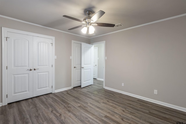 unfurnished bedroom featuring visible vents, crown molding, dark wood-type flooring, and baseboards