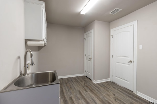 kitchen featuring white cabinetry, visible vents, dark wood-style flooring, and a sink