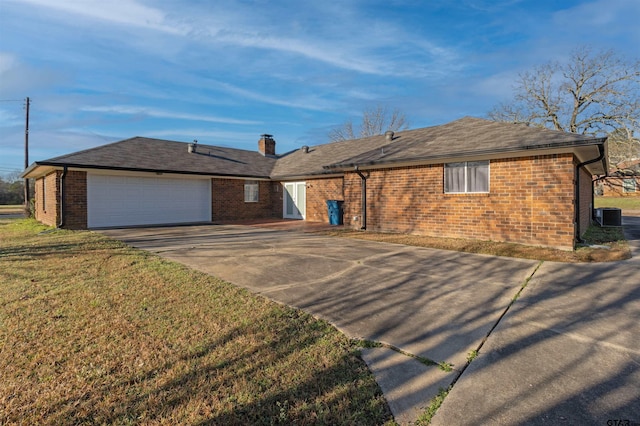 ranch-style home with a front yard, driveway, central AC, a garage, and brick siding