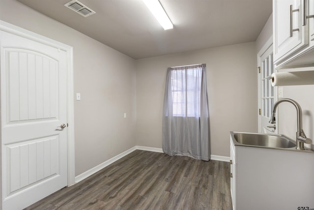 kitchen with visible vents, dark wood-type flooring, a sink, white cabinetry, and baseboards