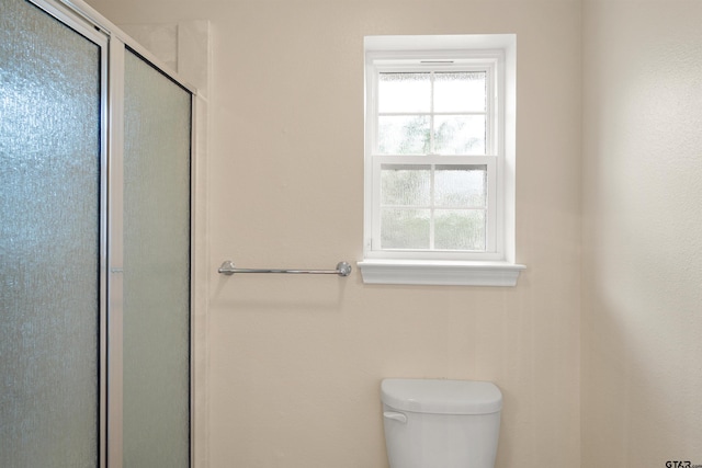 bathroom with a shower with shower door and toilet