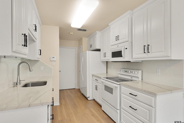 kitchen featuring sink, white cabinetry, light stone countertops, white appliances, and light hardwood / wood-style floors