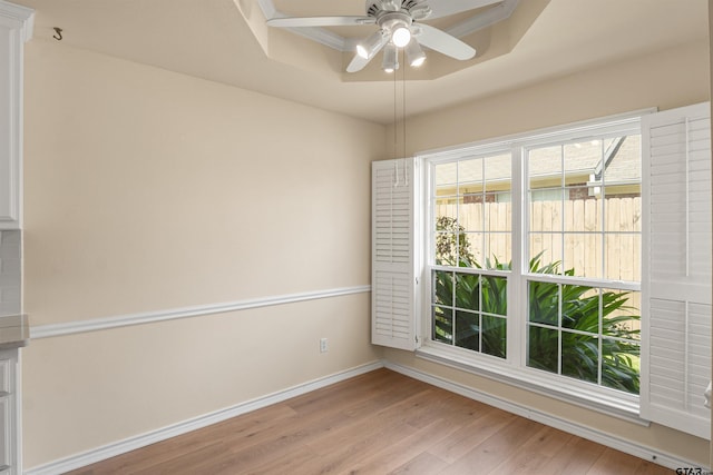 spare room with ceiling fan, light hardwood / wood-style flooring, and a tray ceiling