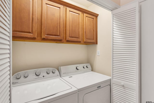 clothes washing area featuring cabinets and washing machine and dryer