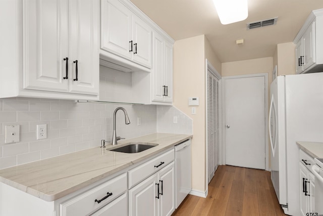 kitchen with white appliances, light hardwood / wood-style floors, white cabinetry, decorative backsplash, and sink