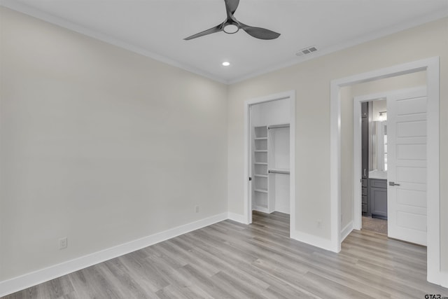 unfurnished bedroom with a walk in closet, ceiling fan, light wood-type flooring, ornamental molding, and a closet