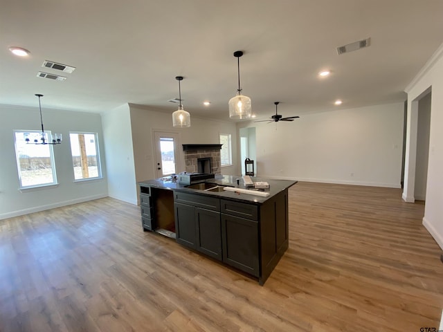 kitchen featuring visible vents, light wood-style floors, open floor plan, and ornamental molding