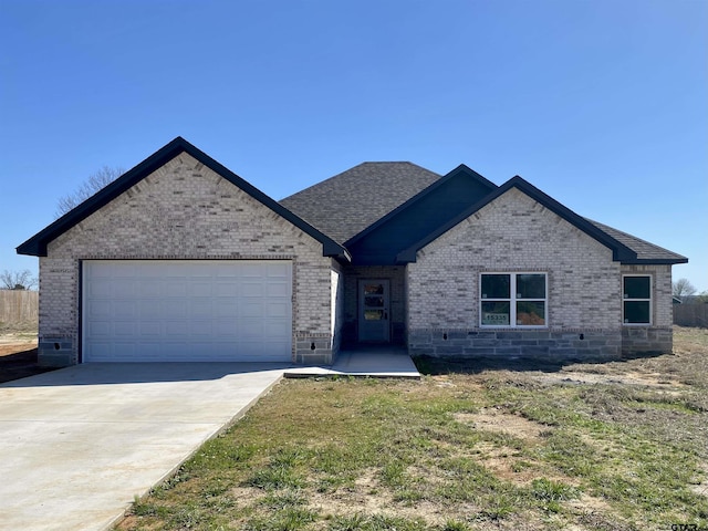 view of front of home featuring brick siding, an attached garage, driveway, and roof with shingles