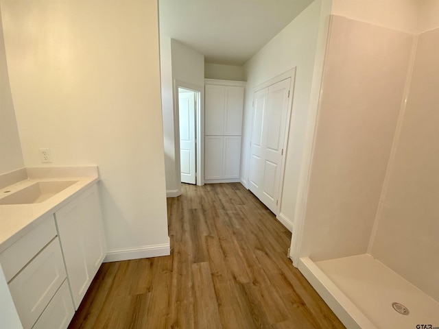 full bathroom with walk in shower, vanity, baseboards, and wood finished floors