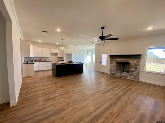 unfurnished living room with visible vents, plenty of natural light, a fireplace, and light wood finished floors