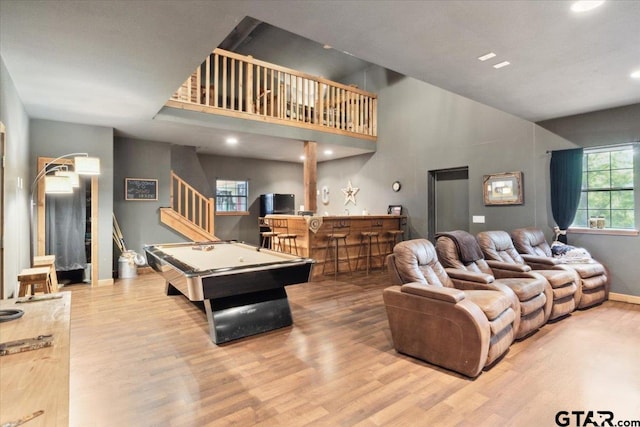 playroom with bar area, pool table, light hardwood / wood-style floors, and a towering ceiling