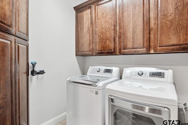 clothes washing area featuring cabinets and washer and dryer