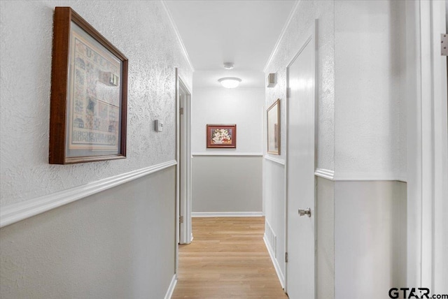 hall with light hardwood / wood-style floors and crown molding